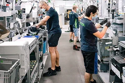 In the spacious plant, employees assemble power tools at modern workstations.