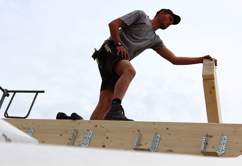 Ein Zimmermann bringt einen Dachbalken in Position.