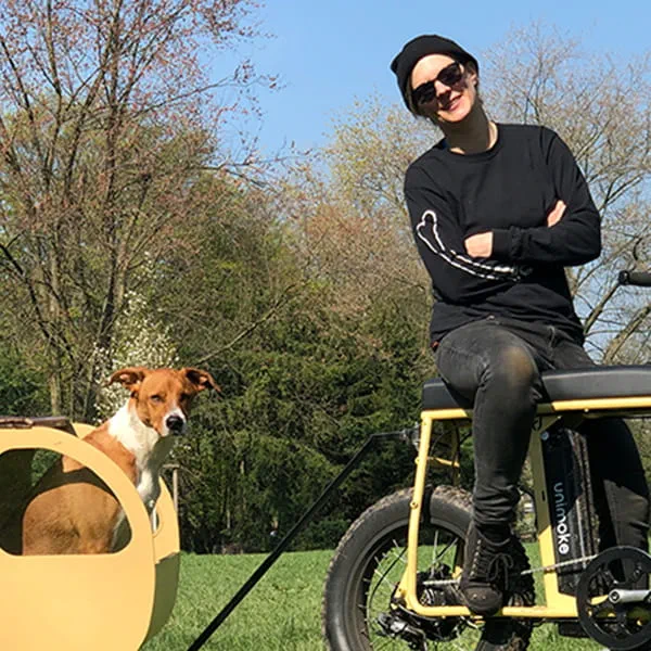 Maker Laura Kampf on her self-built bicycle with her dog Smudo in a tiny trailer.