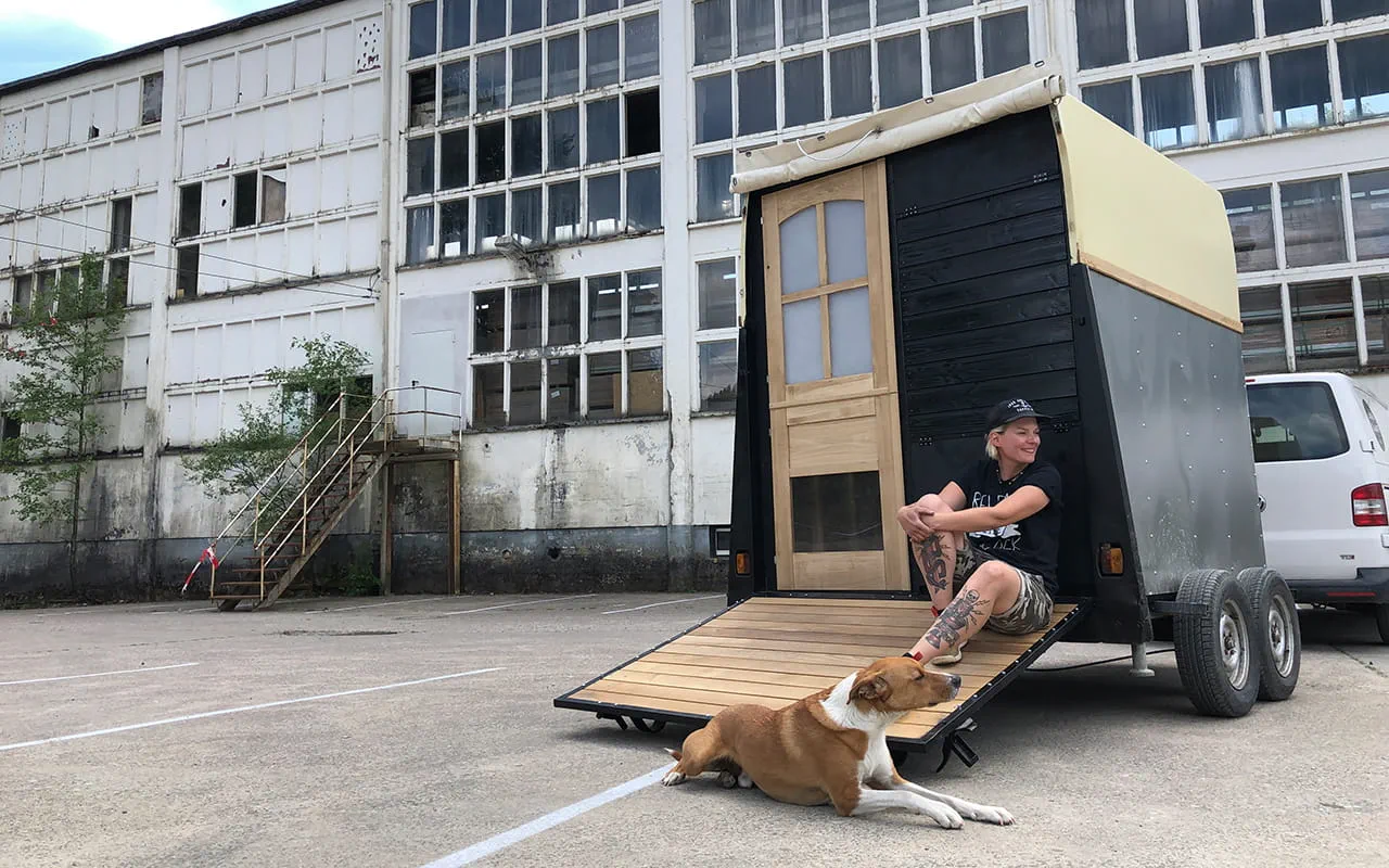 Maker Laura Kampf sitting on a trailer with her dog Smudo.