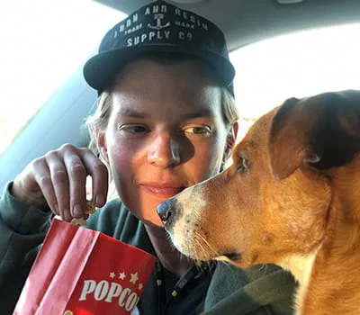 Laura Kampf eating a packet of popcorn with her dog Smudo.