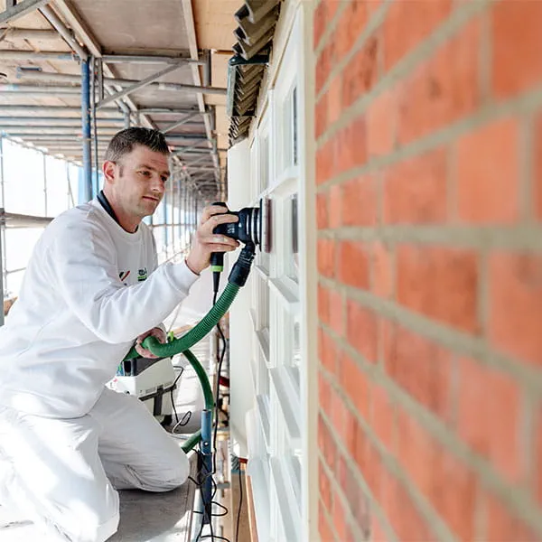 A Wolters employee works to refurbish a window.