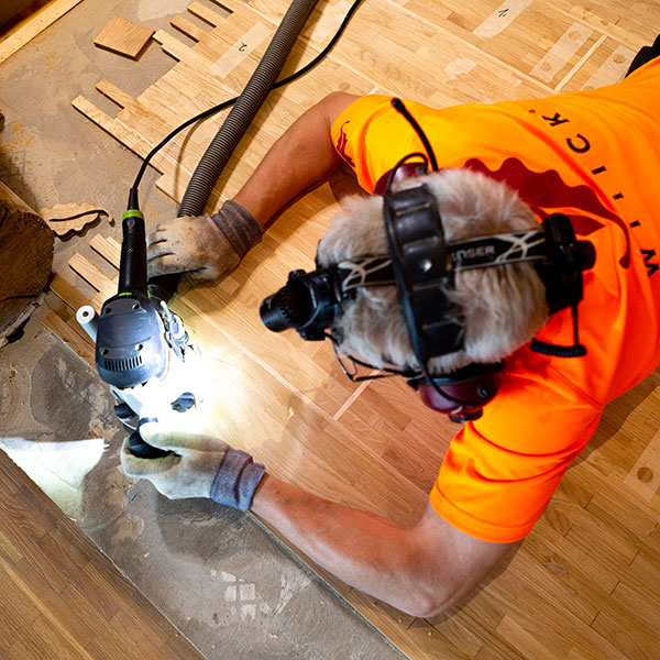 Der finnische Parkettleger bearbeitet den Holzboden mit der Festool Oberfräse