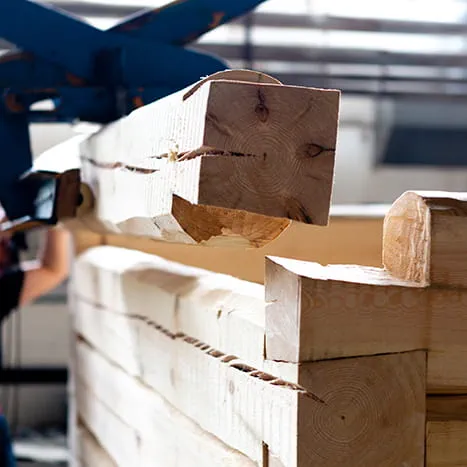 A wooden beam is lifted into place by crane.