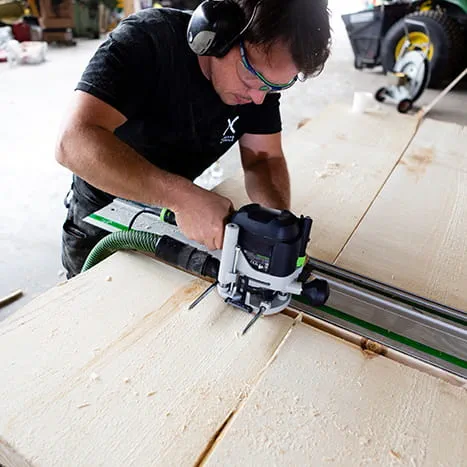 A sauna builder machining a surface with a Festool router.