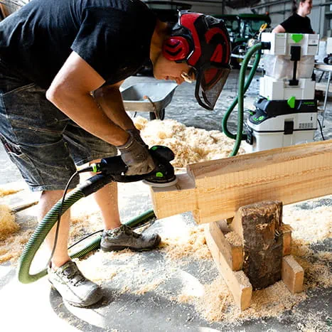 A sauna builder sanding a wood surface with the ROTEX 150 from Festool.